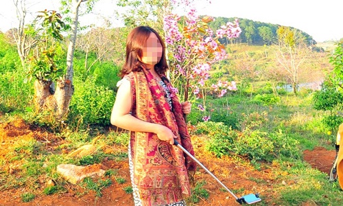 Người phụ nữ chụp ảnh với cành hoa bẻ từ cây anh đào Đà Lạt