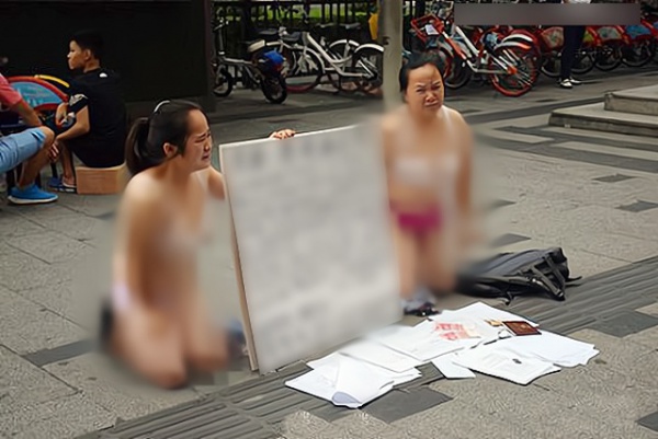 Hai người phụ nữ bán khỏa thân, quỳ trên phố xin tiền, lý do phía sau gây bất ngờ